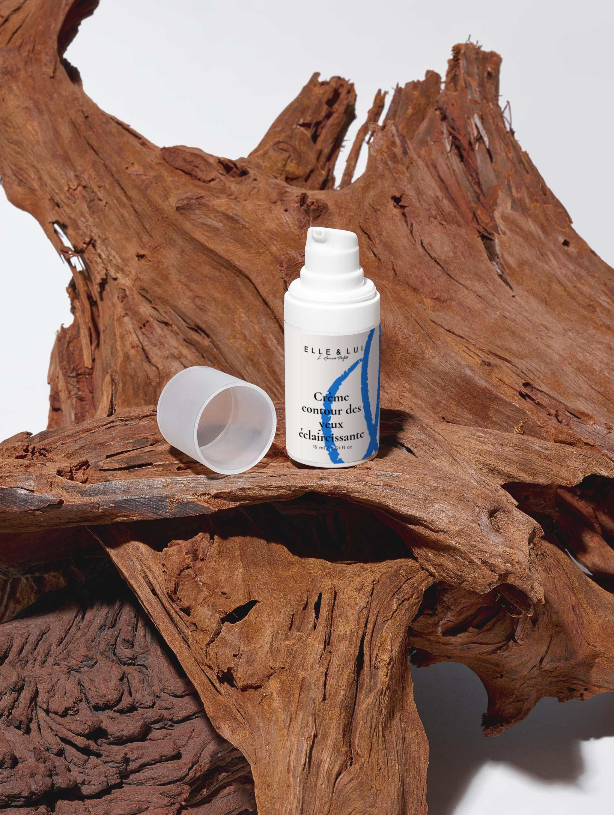 Crème contour des yeux éclaircissante posée sur un bois naturel dans le cadre de la Boîte de collection Éclat rajeunissant