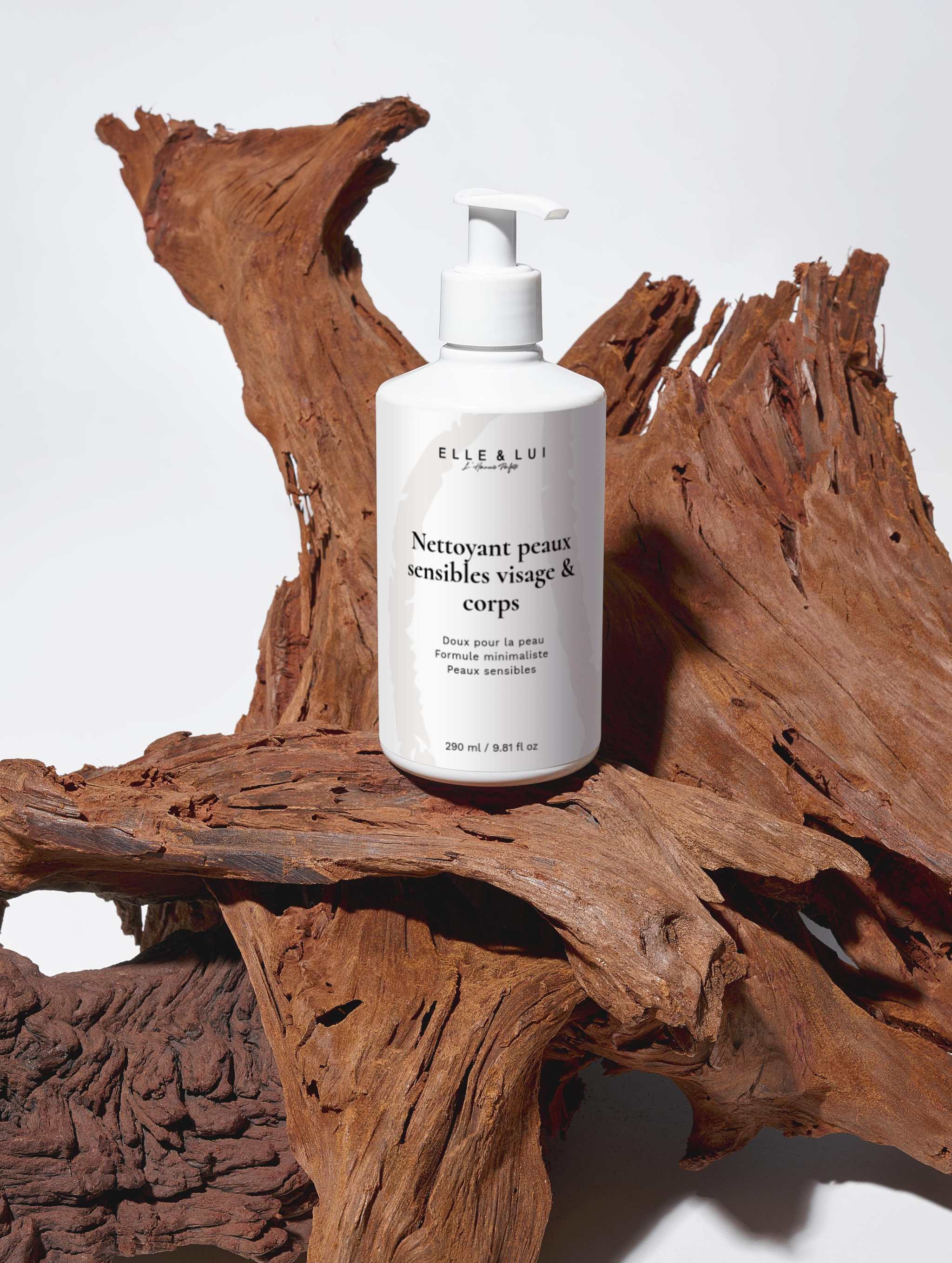 Nettoyant peaux sensibles visage et corps en flacon pompe blanc posé sur bois naturel, soin doux hydratant et apaisant